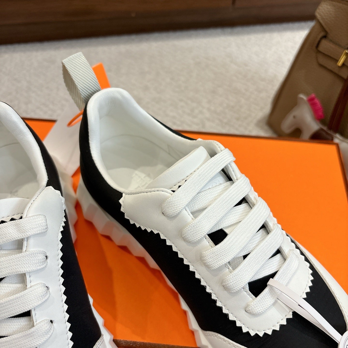 Hermes unisex sneaker, white-and-black colorblock with lace-up front and white serrated sole.