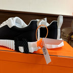 Hermes unisex sneakers, black-and-white uppers with white laces and thick tread sole.