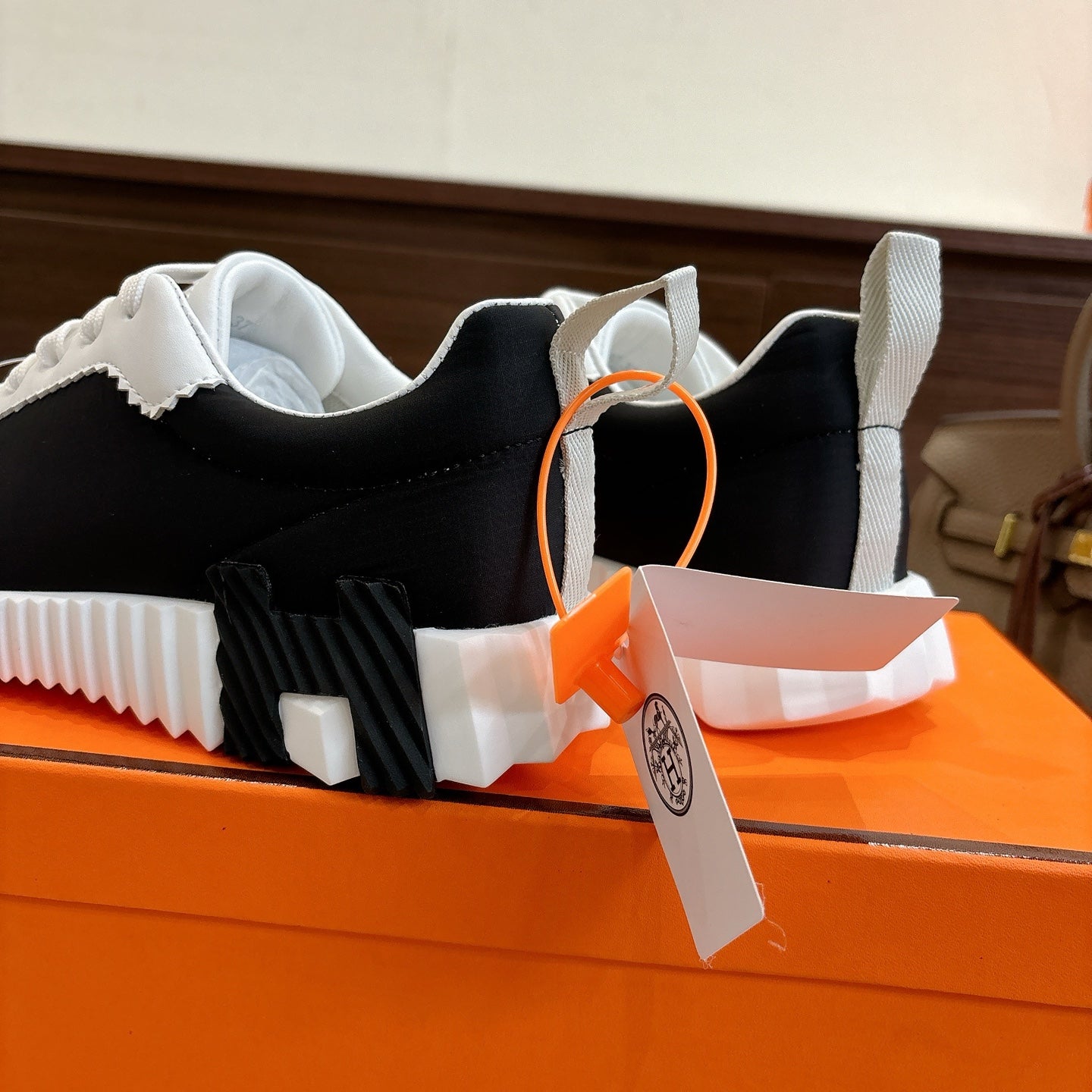 Hermes unisex sneakers, black-and-white uppers with white laces and thick tread sole.