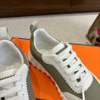 Close-up of white unisex sneaker upper with white laces and side logo badge on olive panel.