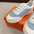Hermes unisex luxury sneakers, close side profile with white upper and light blue textured knit.