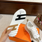 Hermes unisex sneaker sole, white tread with black stripes and tan rubber heel piece.