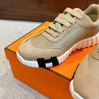 Unisex light tan sneaker close-up with lace-up, textured panels, and chunky white tread sole.