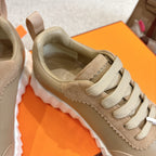 Unisex light tan sneaker close-up: lace-up, padded collar, and smooth suede panels.