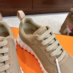 Beige suede sneakers with cream laces, textured side paneling, and white chunky sole