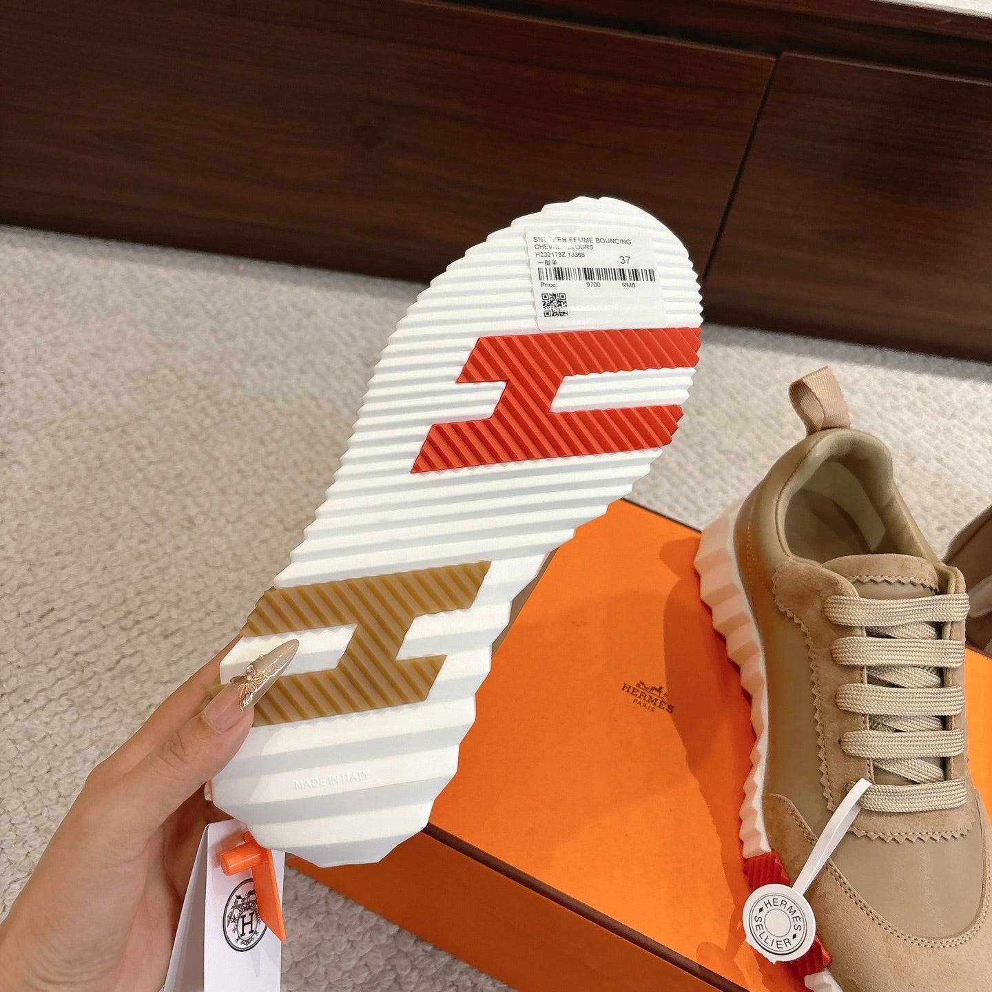 Beige lace-up sneakers with striped outsole, showing tread and logo medallion