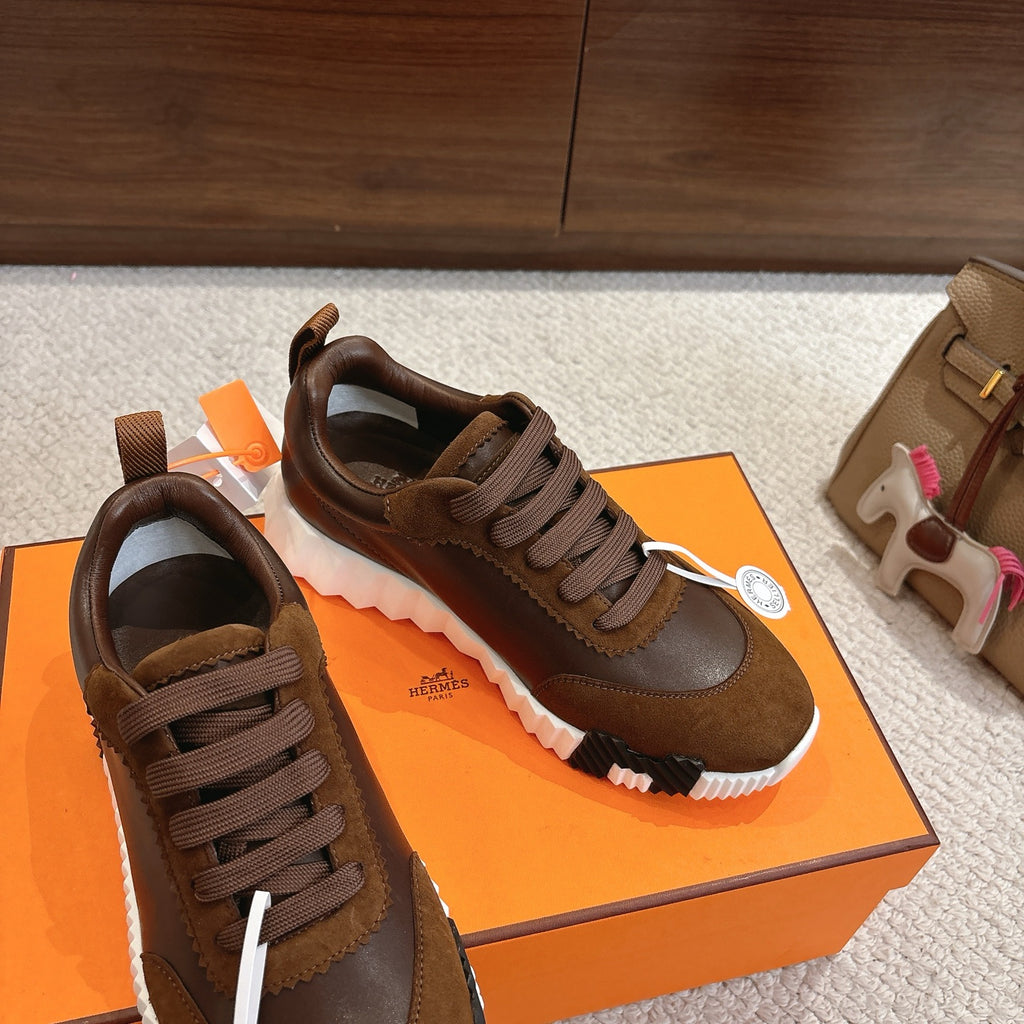 Hermes unisex sneakers on shoebox, brown lace-up design with suede overlays and white tread sole.