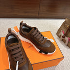 Hermes unisex sneakers on shoebox, brown lace-up design with suede overlays and white tread sole.