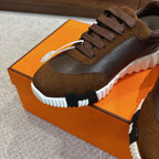 Hermes unisex sneaker close-up, brown leather and suede, lace-up with white textured sole.