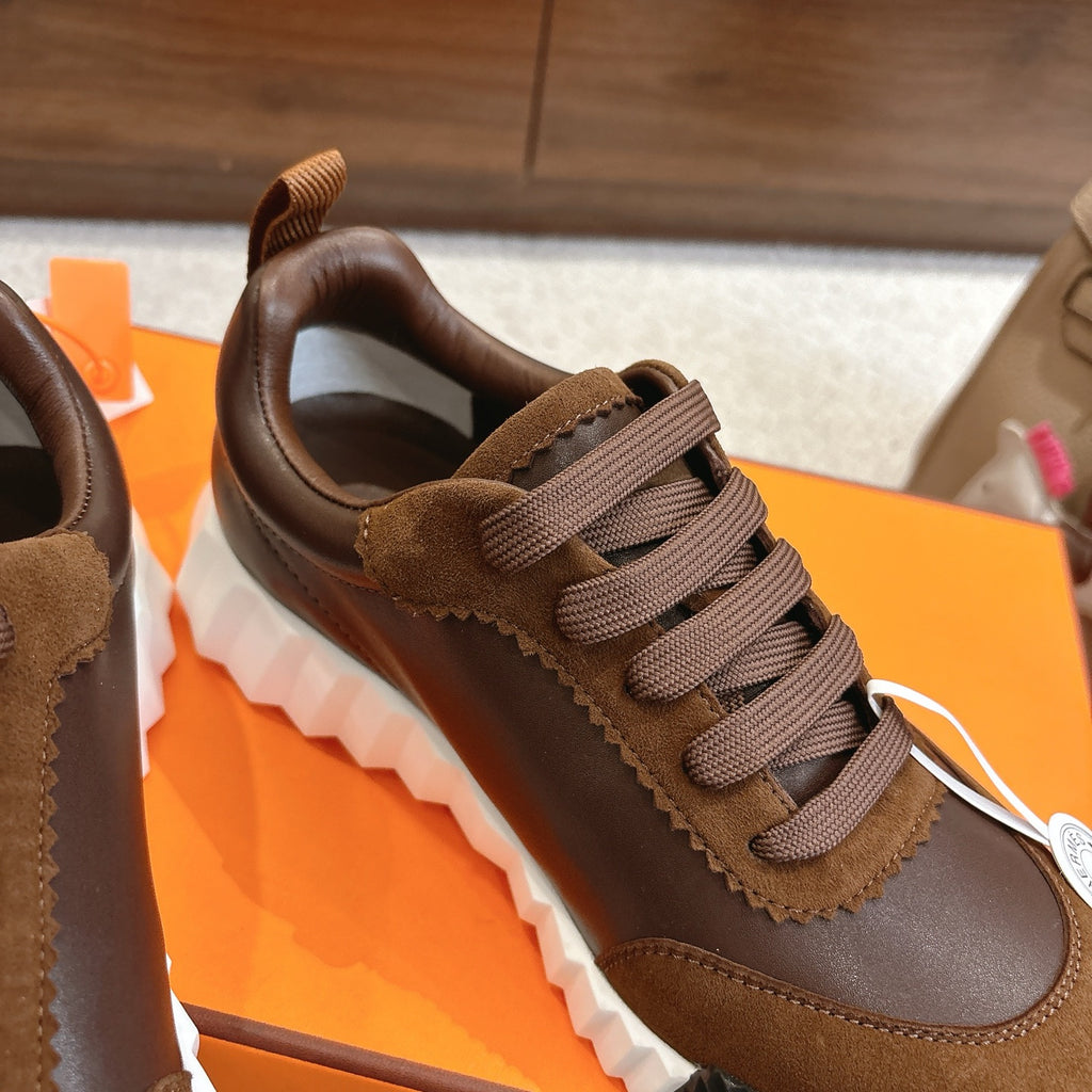 Hermes unisex sneaker close-up, brown suede and leather with lace-up closure and white ridged sole.