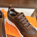 Hermes unisex sneaker close-up, brown suede and leather with lace-up closure and white ridged sole.
