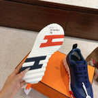 Blue unisex sneaker sole view, white tread with navy stripe and orange accent
