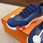Blue unisex sneaker close-up, navy laces, metal logo medallion, white sole