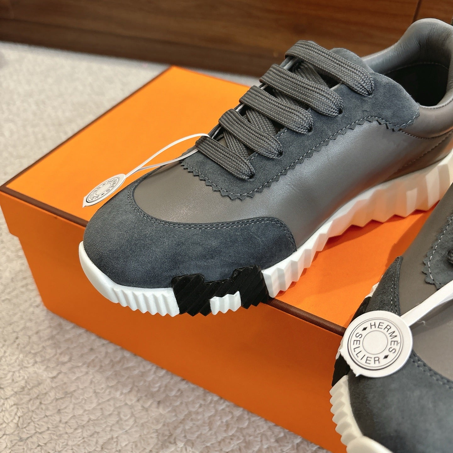 Gray lace-up sneaker upper detail with stitched overlay, gray laces, white sole