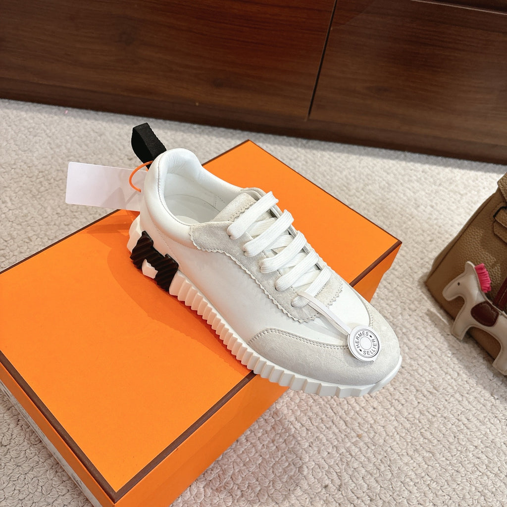 Hermes white unisex sneaker, close side view with white laces and black tread accent
