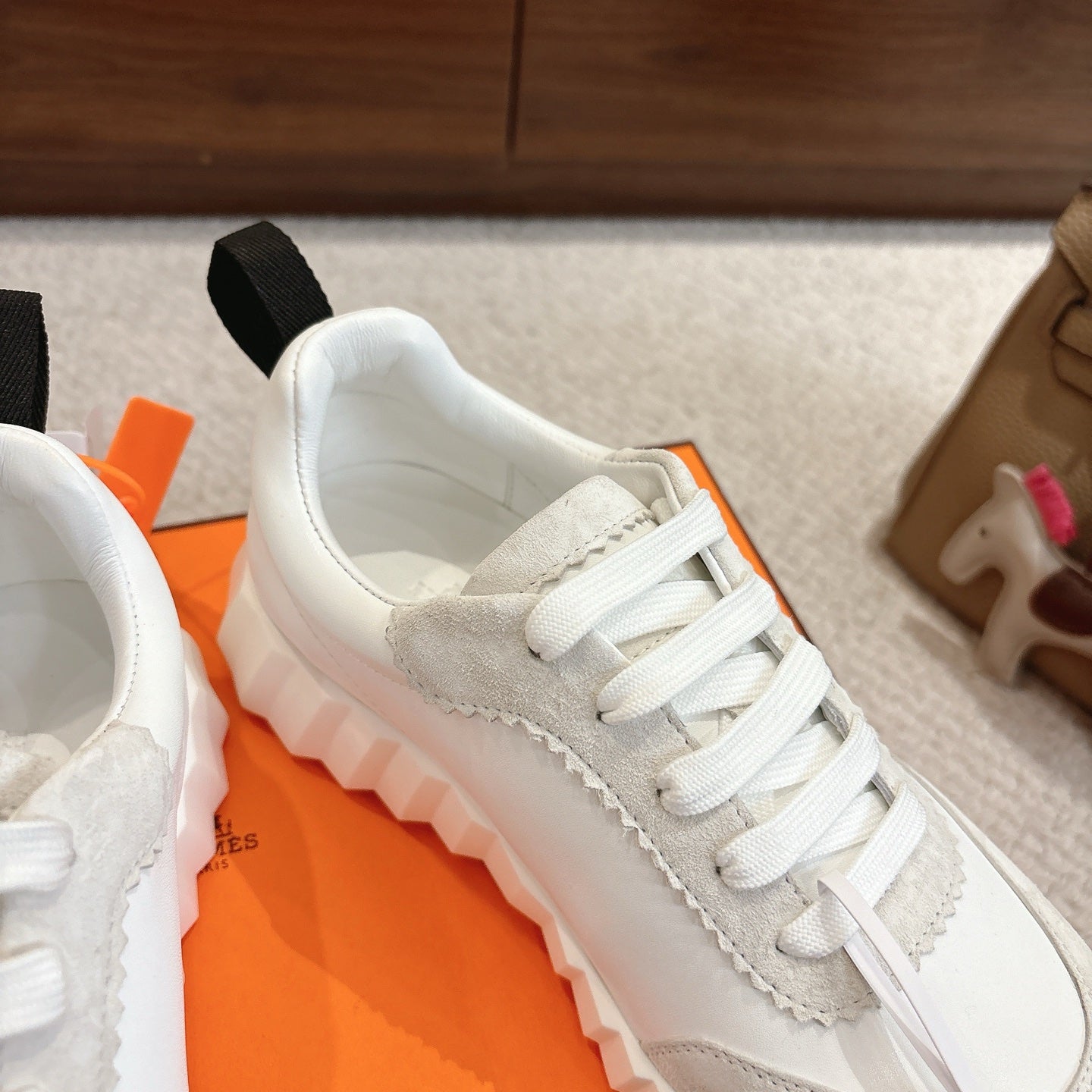 Hermes white unisex sneaker close-up, side profile with white laces and textured midsole