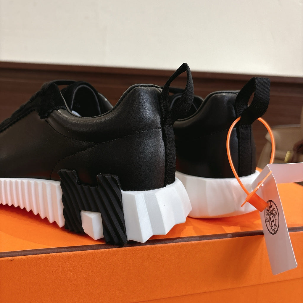 Hermes unisex sneakers side view: black upper with chunky white sole and heel tab
