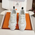 White low-top sneakers with white laces and padded tongues, shown in box with two pairs.