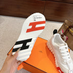 White sneaker sole and heel side view with red logo marks over thick white tread.