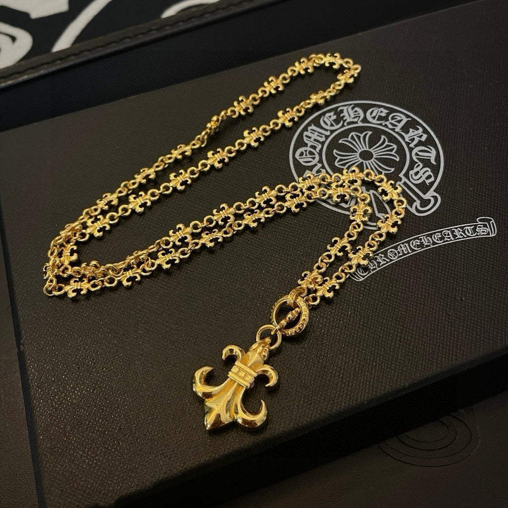 Gold-tone pendant necklace with long chain and fleur de lis charm on box