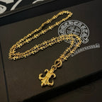 Gold-tone pendant necklace with long chain and fleur de lis charm on box