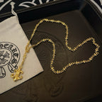 Gold-tone pendant necklace with fleur de lis charm resting on jewelry box