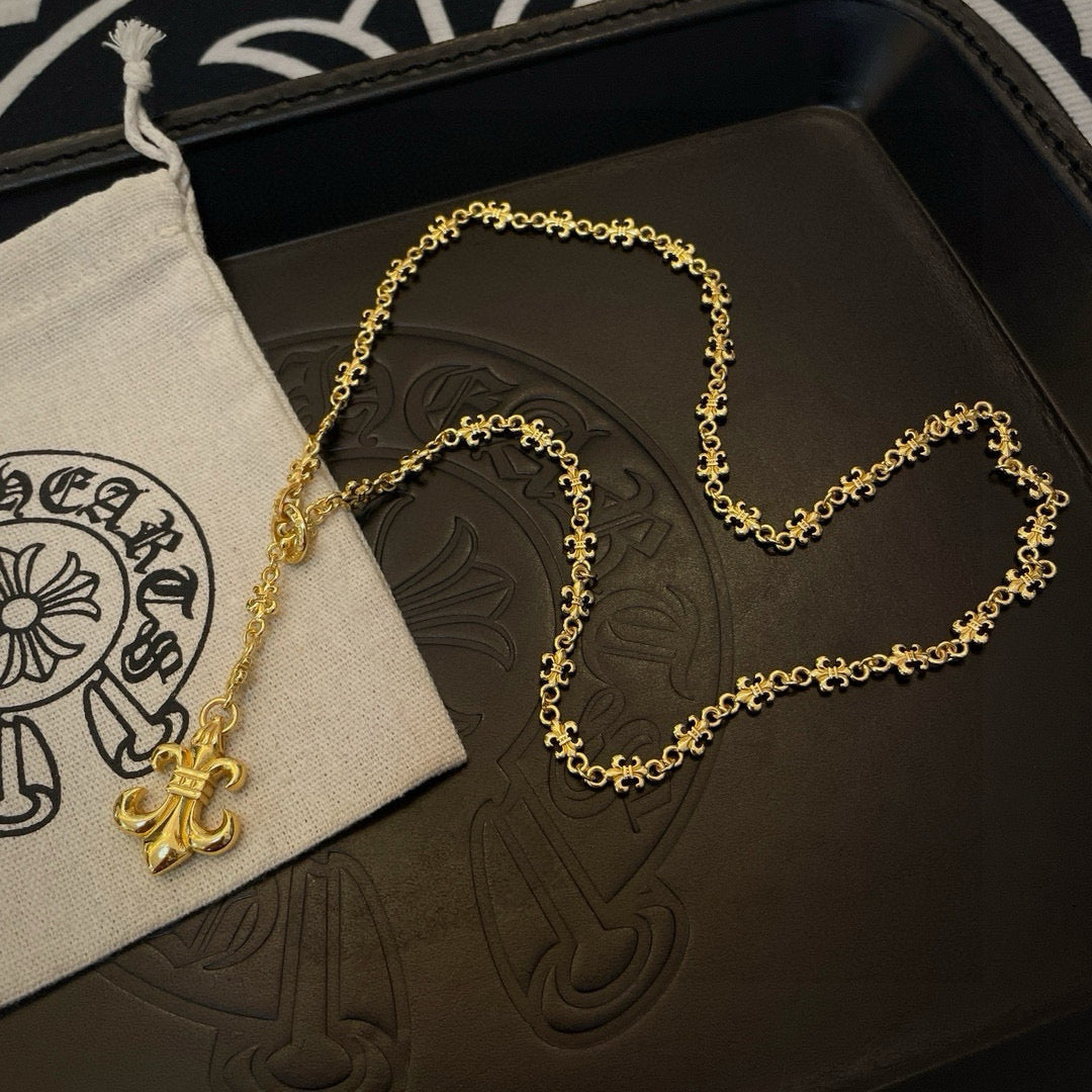 Gold-tone pendant necklace with fleur de lis charm resting on jewelry box