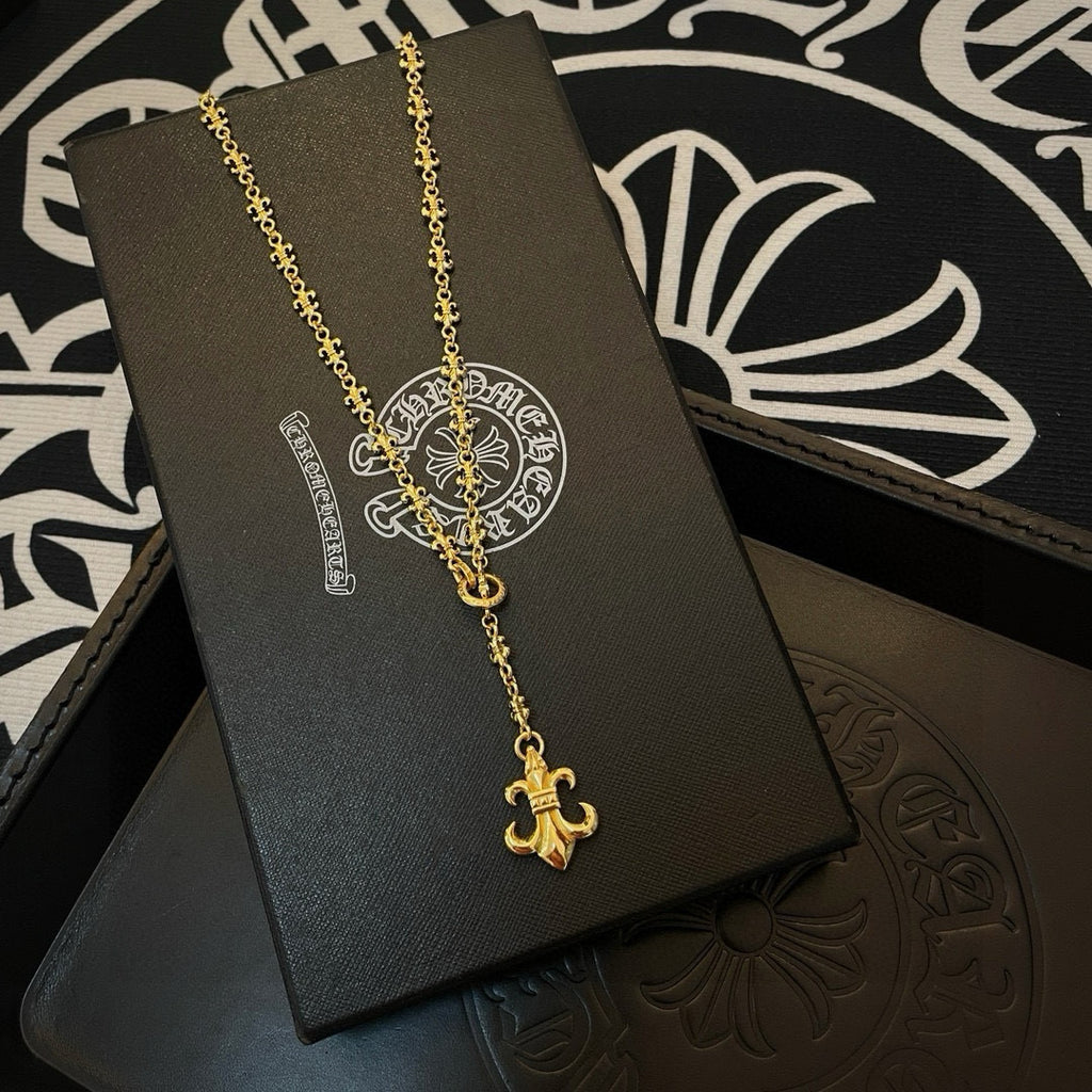 Gold-tone pendant necklace with ornate medallion and fleur de lis on display card