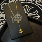 Gold-tone pendant necklace with ornate medallion and fleur de lis on display card