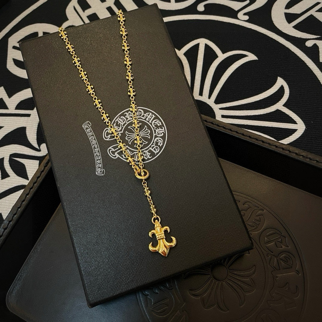 Gold-tone pendant necklace with ornate medallion and fleur de lis on display card