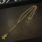 Gold-tone pendant necklace with fleur de lis charm detail on black case