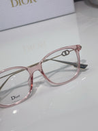 Dior glasses close-up with rose pink acetate frame and gold detail, clear lens