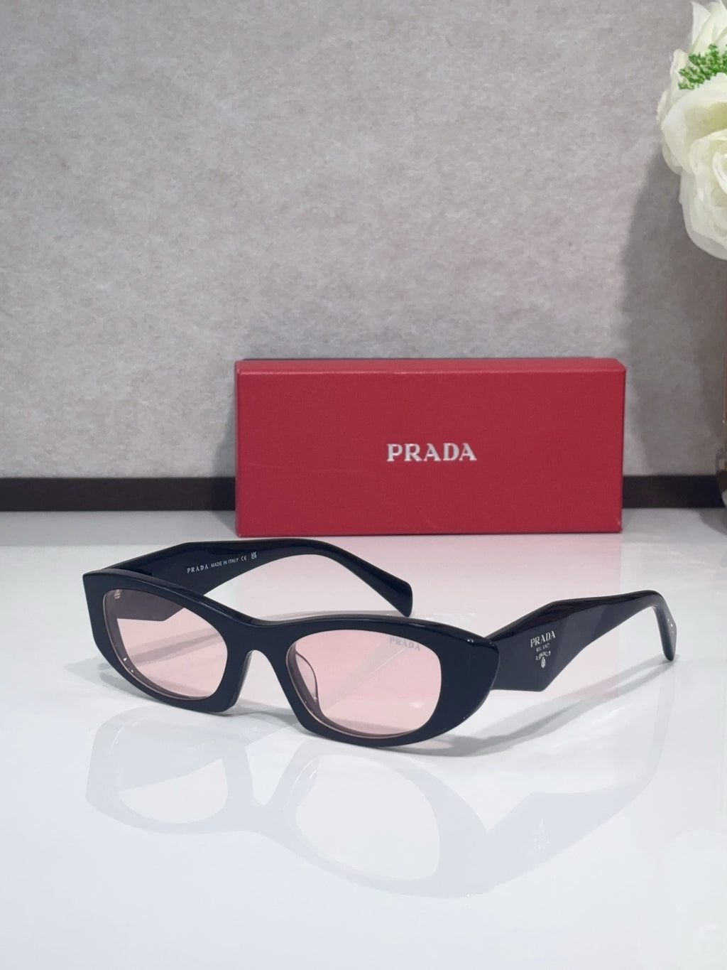 Cat-eye glasses with dark frames and pink-tinted lenses