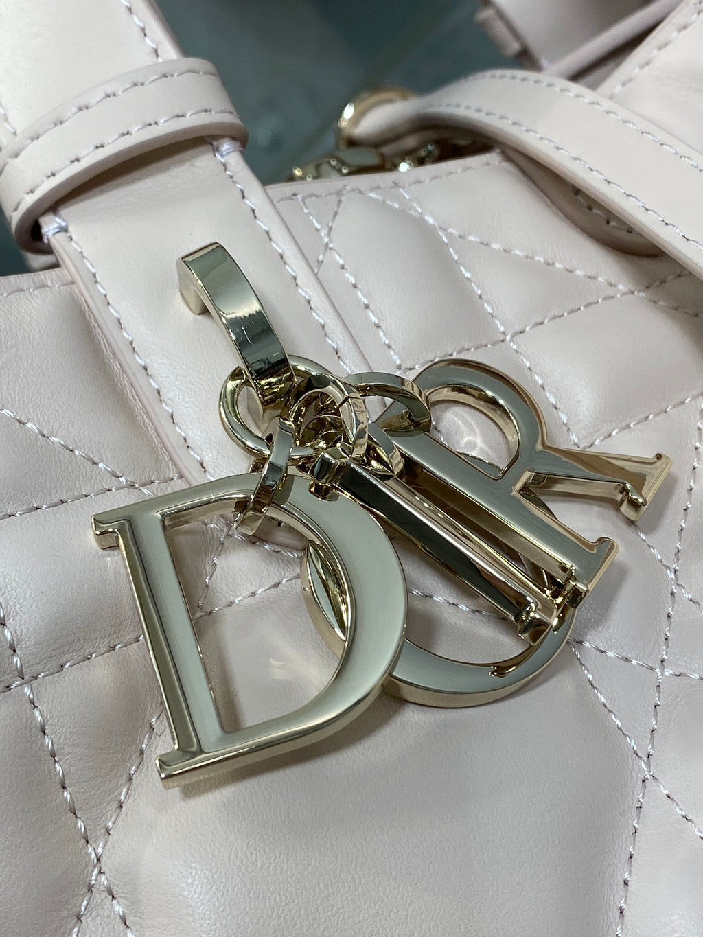 White quilted handbag close-up of Dior emblem and strap hardware