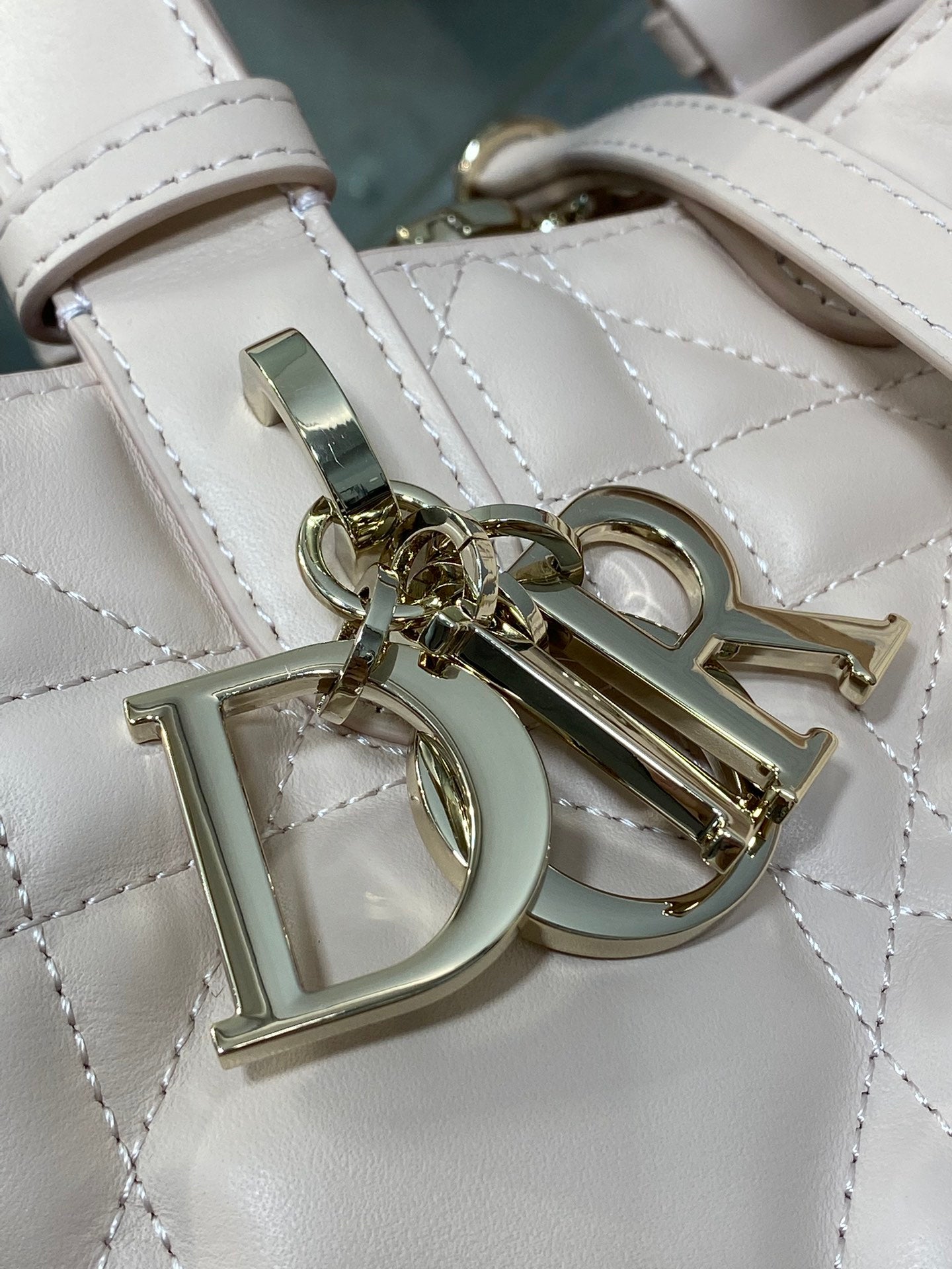 White quilted handbag close-up of Dior emblem and strap hardware