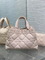 Light pink quilted handbag with top handles and front emblem