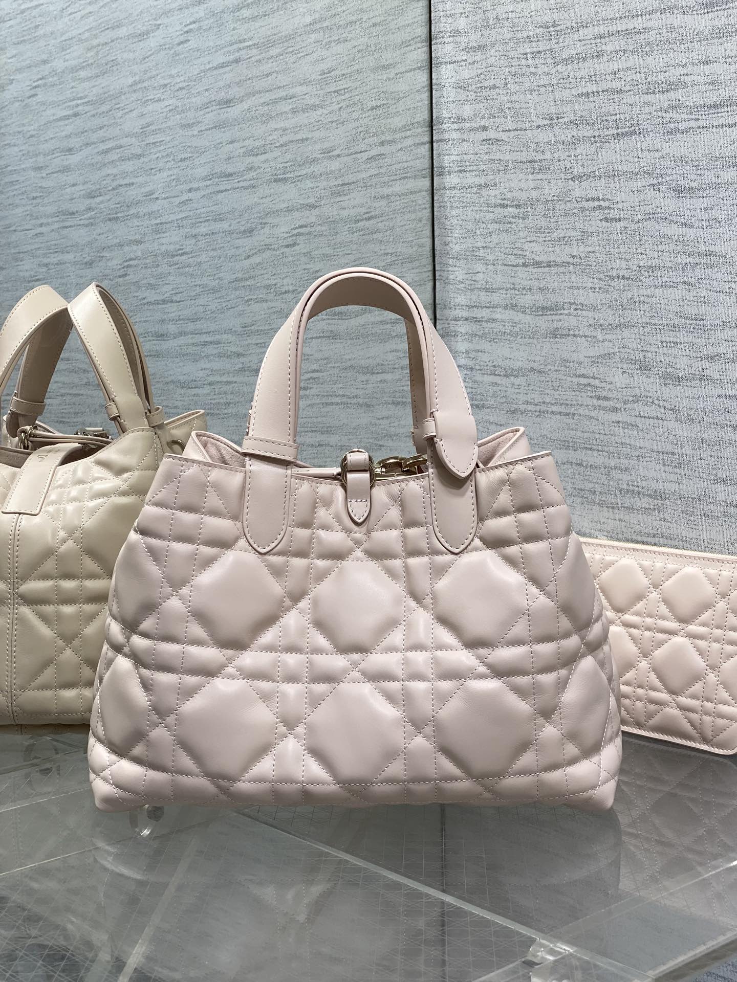 Light pink quilted handbag with top handles and front emblem