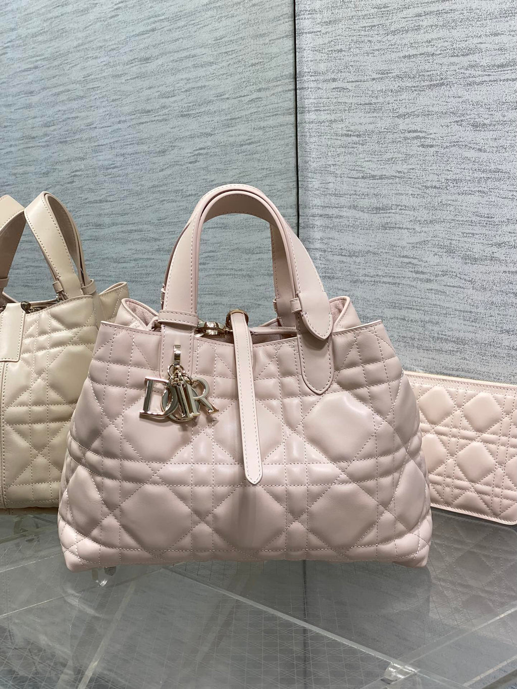 Light pink quilted handbag with top handles and front Dior logo charm