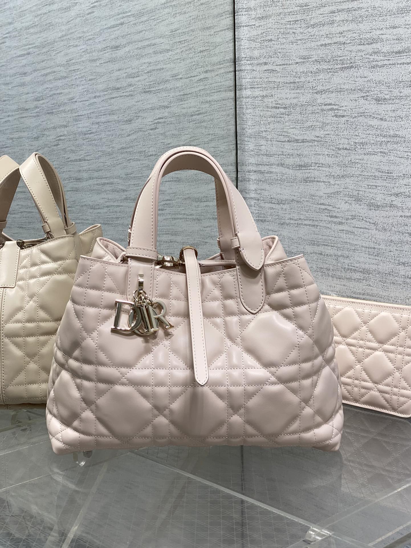 Light pink quilted handbag with top handles and front Dior logo charm