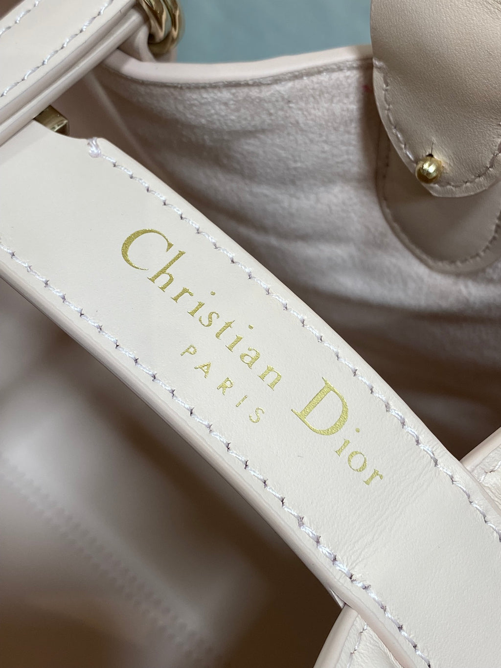 White leather strap with gold “Christian Dior Paris” lettering and stitching