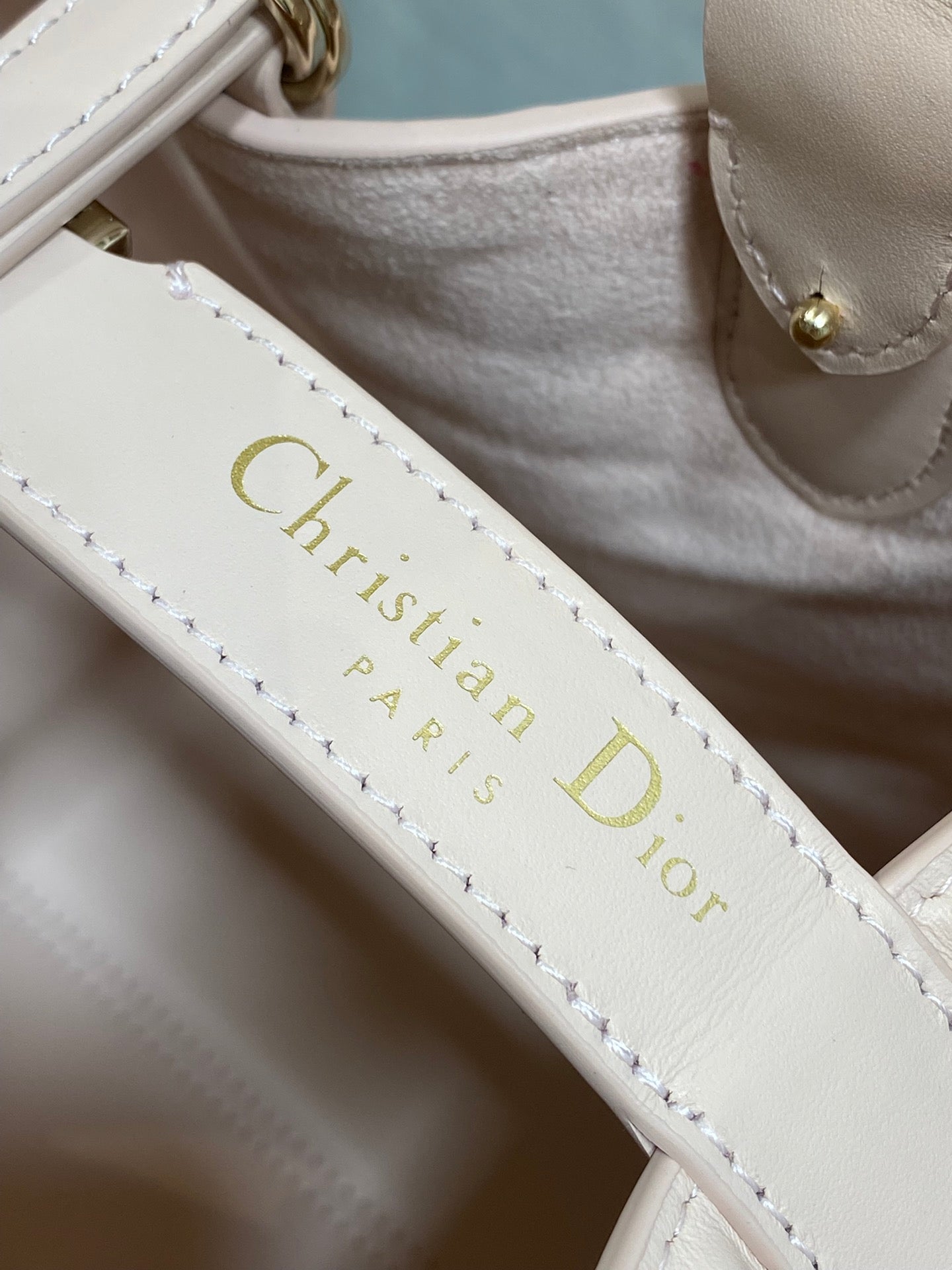 White leather strap with gold “Christian Dior Paris” lettering and stitching