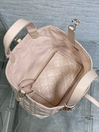 Light pink quilted handbag open with interior zip pocket and side handles