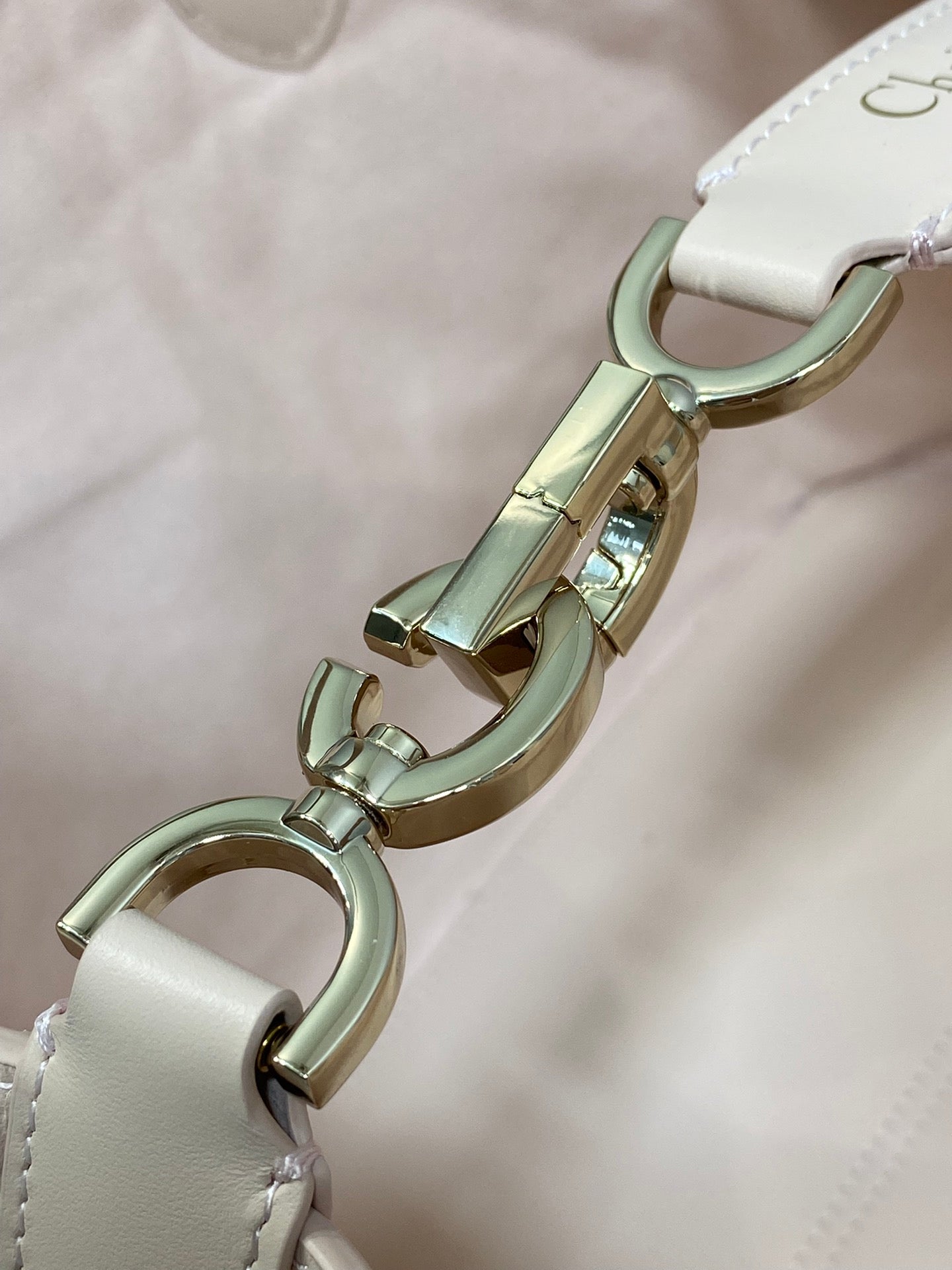 White handbag clasp and rings with gold-tone hardware on the strap