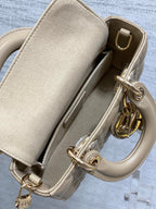 Beige handbag interior view with flap pocket divider and gold-tone clasp