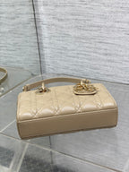 Cream quilted handbag with top handles and gold-tone emblem on flap