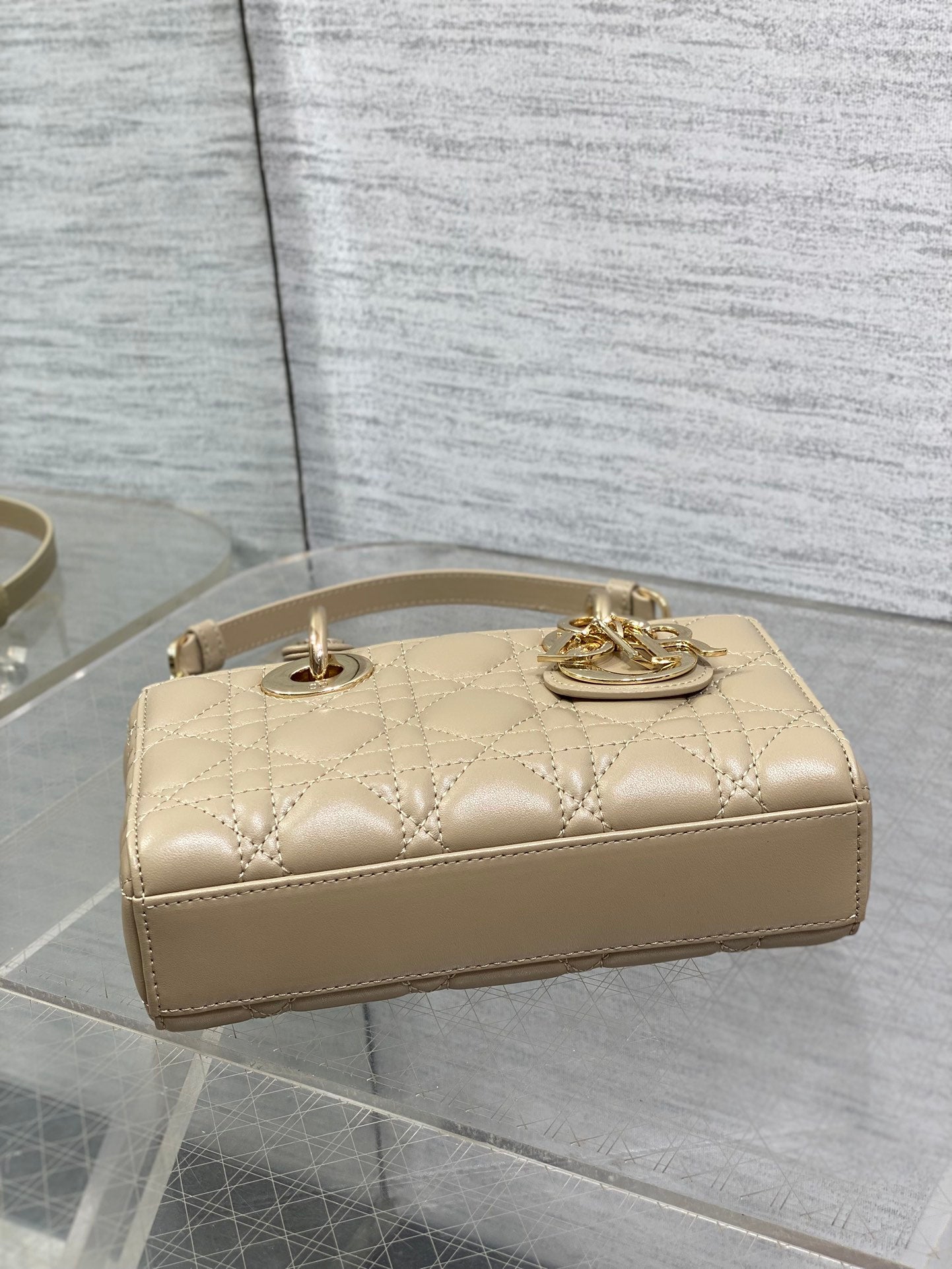 Cream quilted handbag with top handles and gold-tone emblem on flap