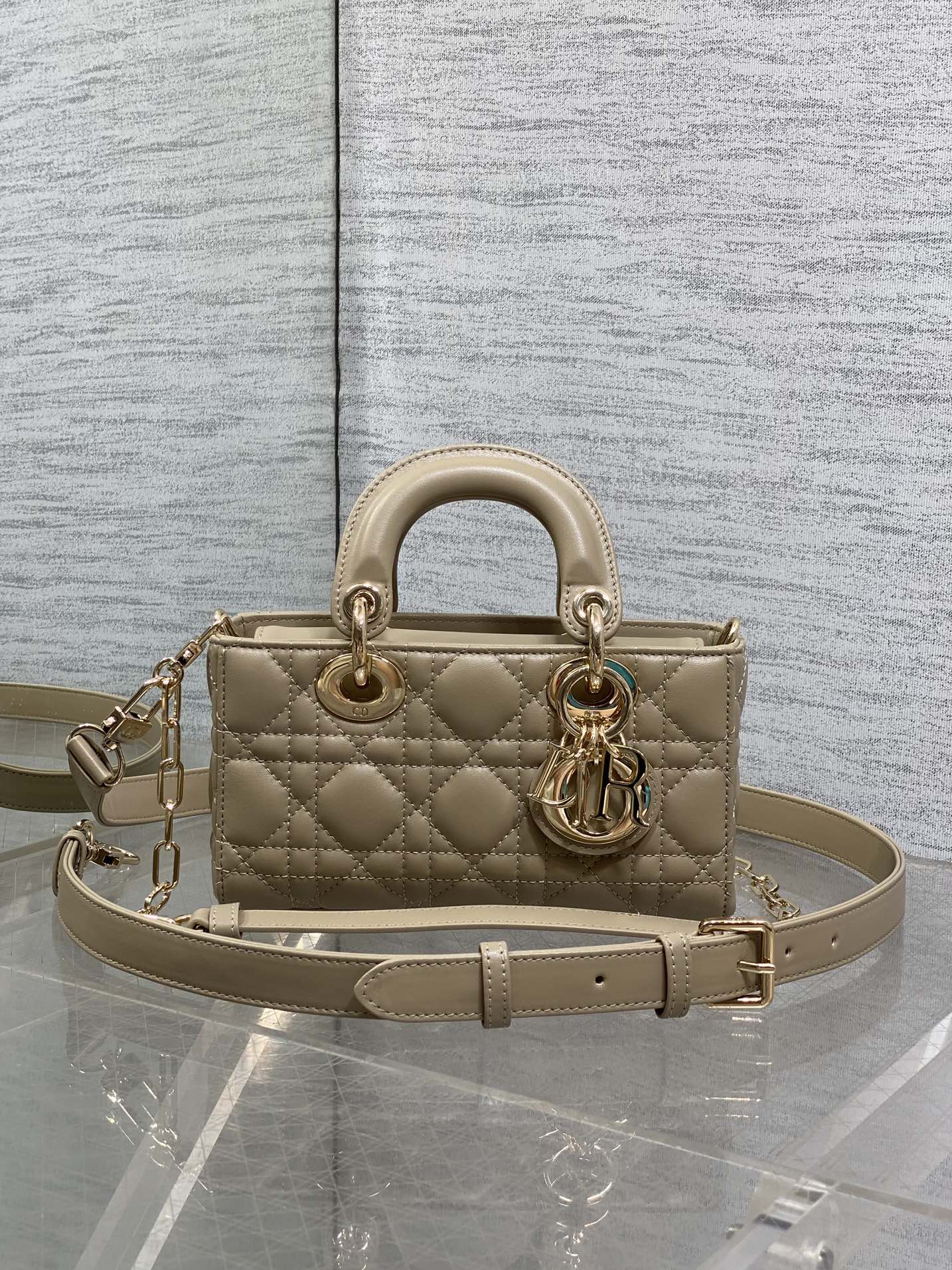 Beige quilted handbag with top handles, gold-tone hardware, and adjustable shoulder strap
