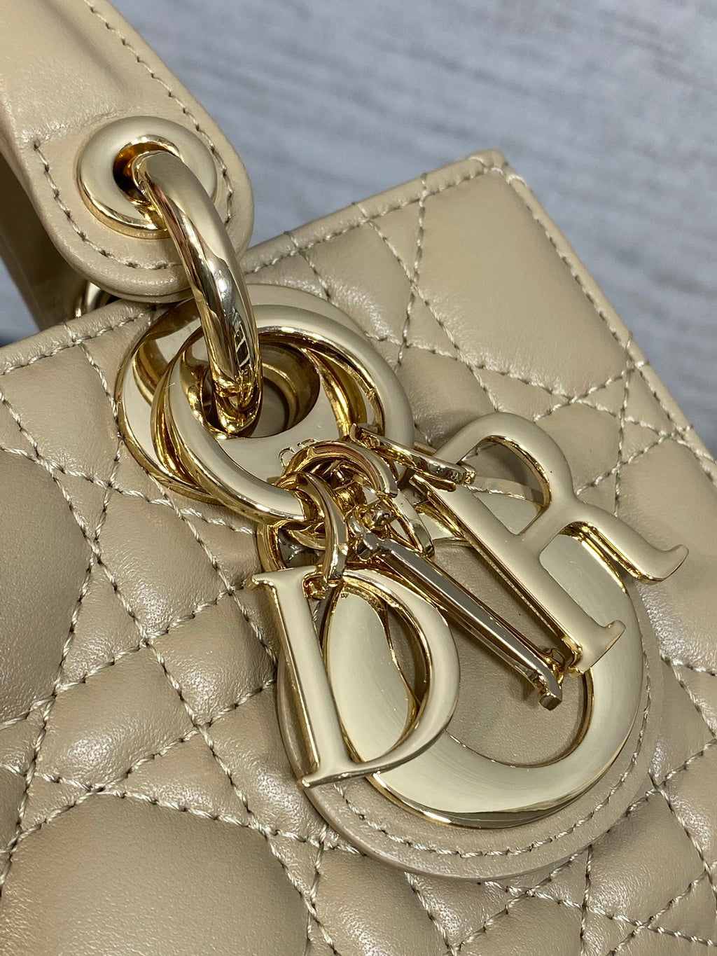 Gold-tone charm and clasp detail on quilted beige handbag