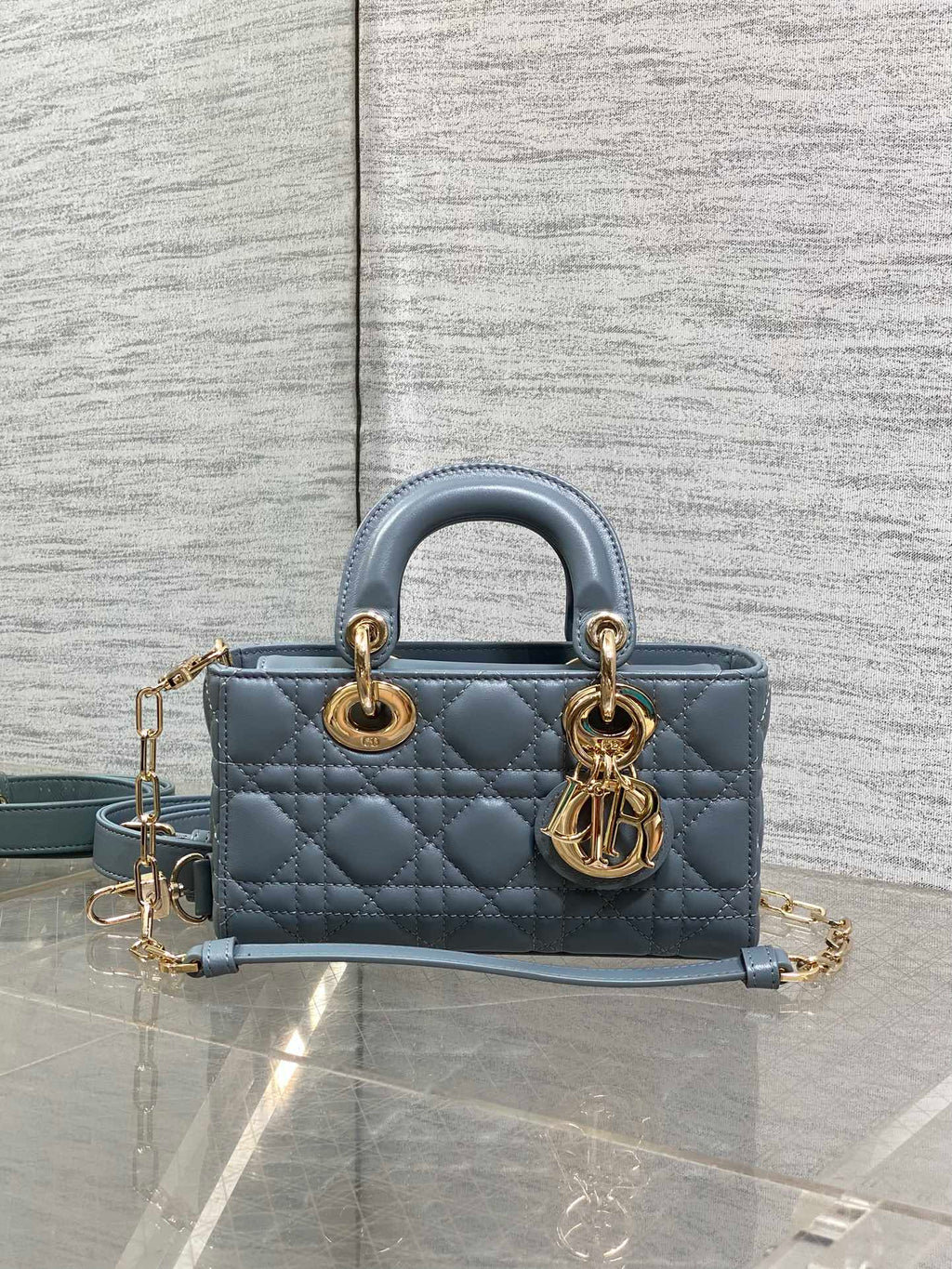 Dior quilted handbag with top handles, gold rings, and adjustable blue crossbody strap