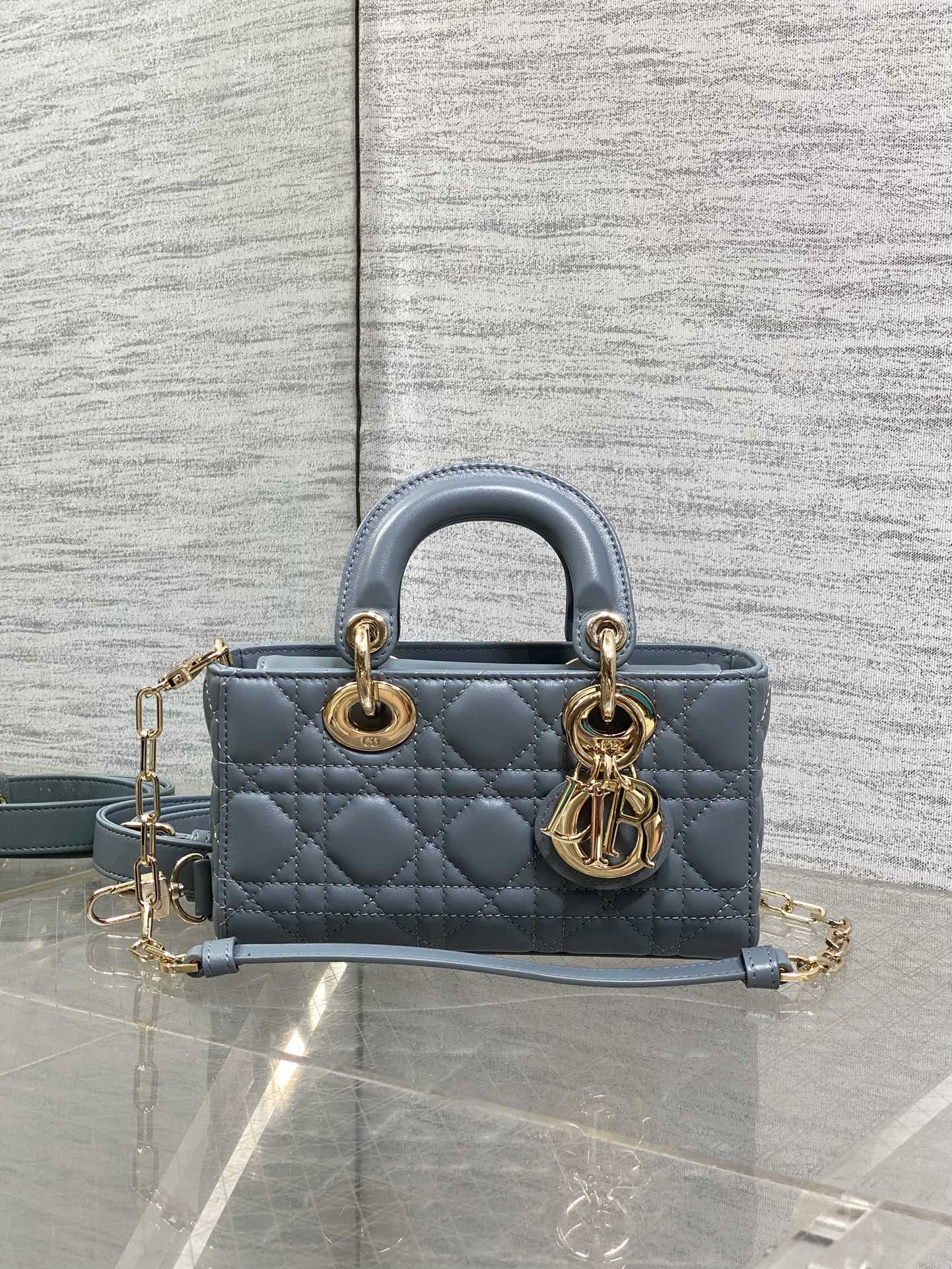 Dior quilted handbag with top handles, gold rings, and adjustable blue crossbody strap